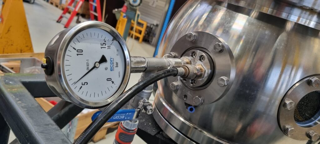 Pressure gauge connected to a stainless steel Techno-G valve housing in the workshop